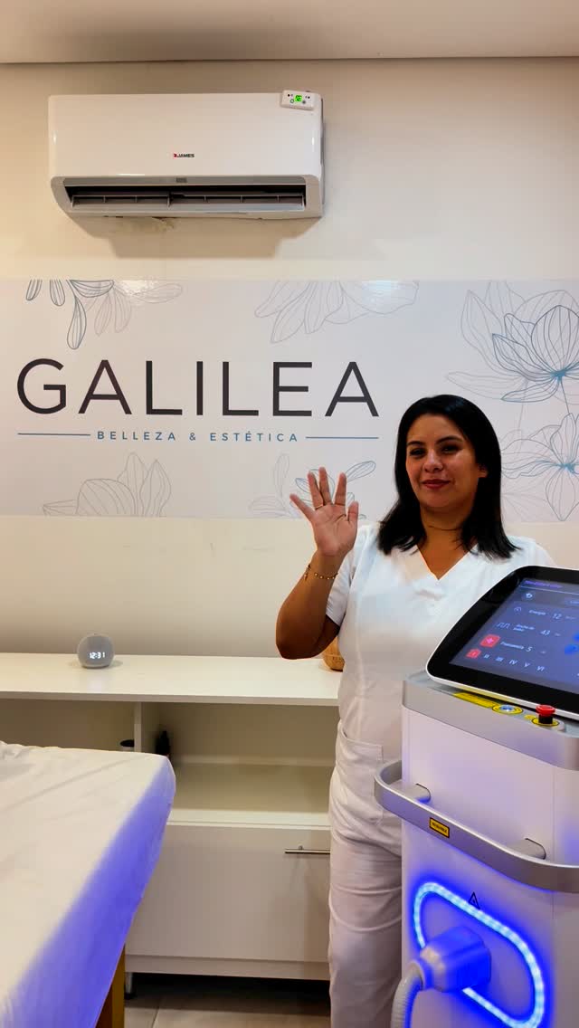 La profesional de Galilea saluda junto al equipo láser, frente a la pared con el logo GALILEA Belleza & Estética